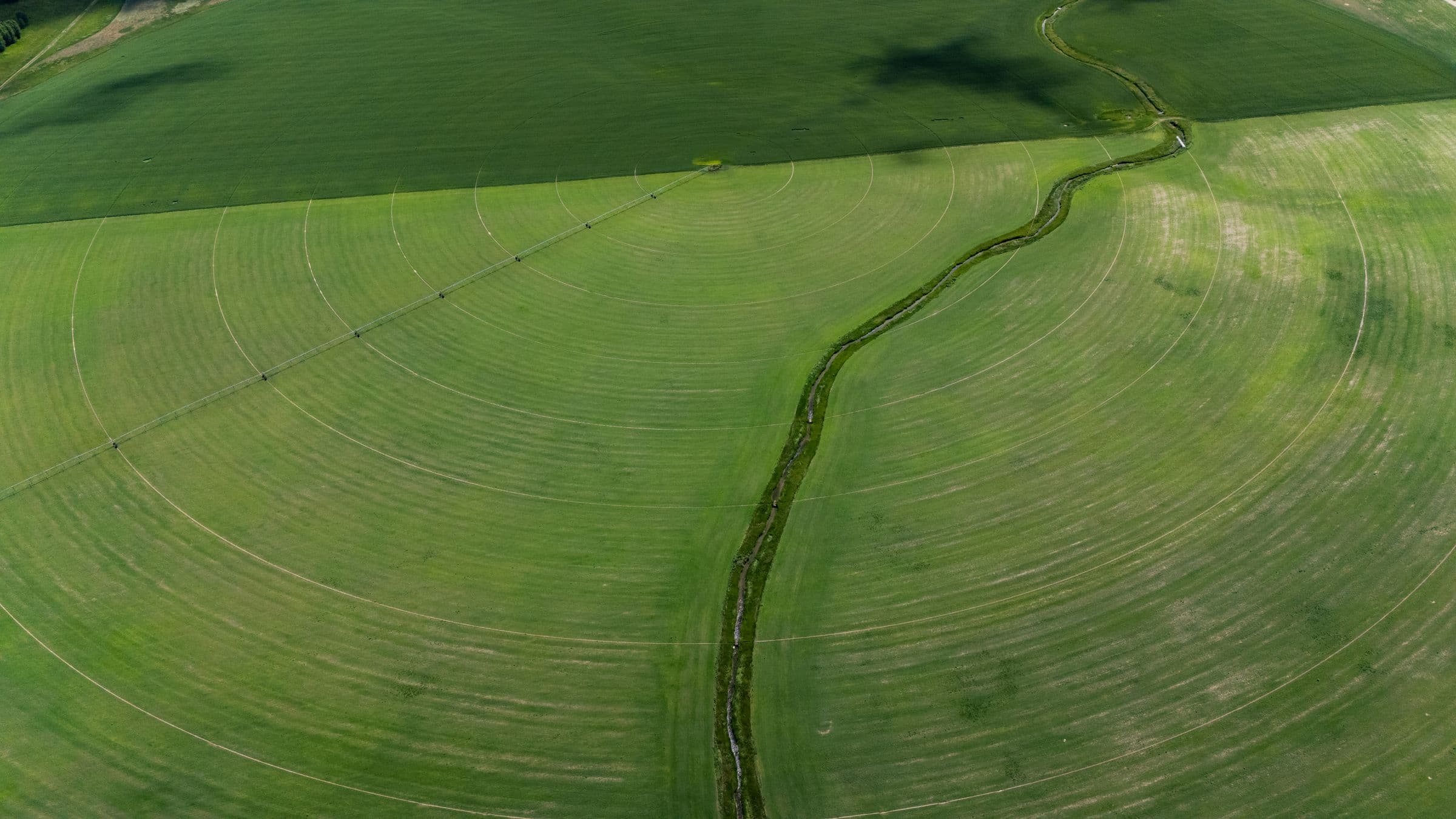 Lavoura irrigada por pivô com um córrego, em cor natural